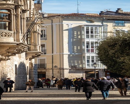 Pedestrians walking along a sunny city street in Spain with typical architecture